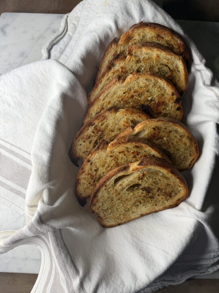 Sourdough garlic toast in a basket lined with a tea towel ready to serve. 