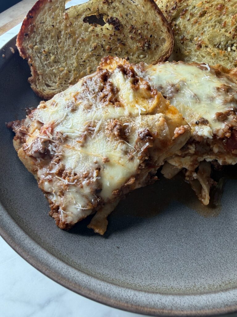 A warm plate of homemade sourdough lasagna with sourdough garlic bread. 