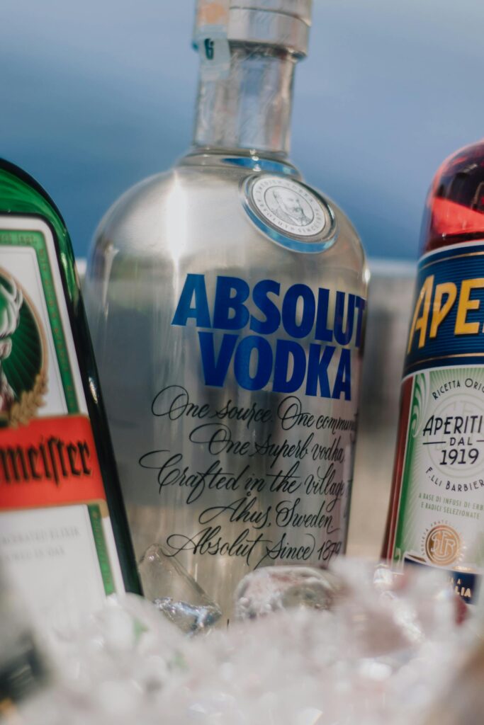 A close-up shot of Absolut Vodka, Jagermeister, and Aperol bottles with ice cubes.