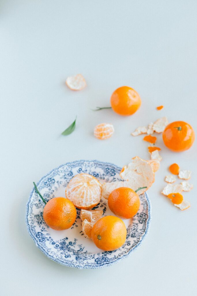 High-angle view of fresh mandarin oranges on a decorative ceramic plate with peels.