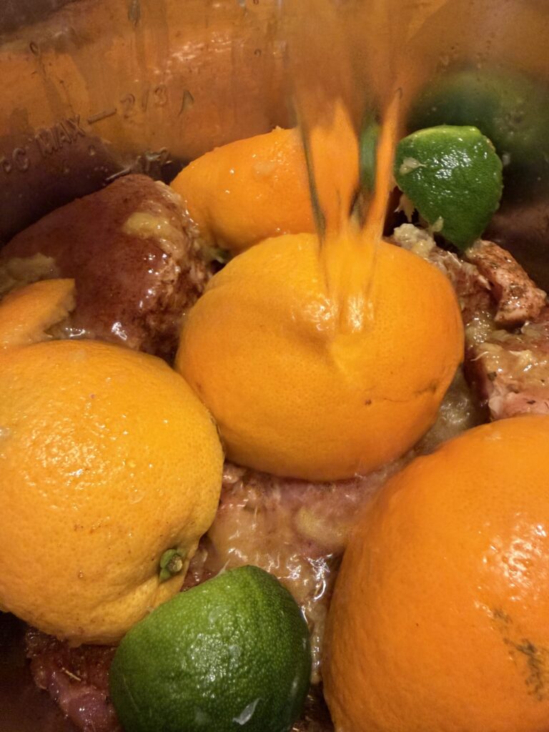 Water is being poured over orange and lime peels preparing to make pork carnitas in the instant pot. 