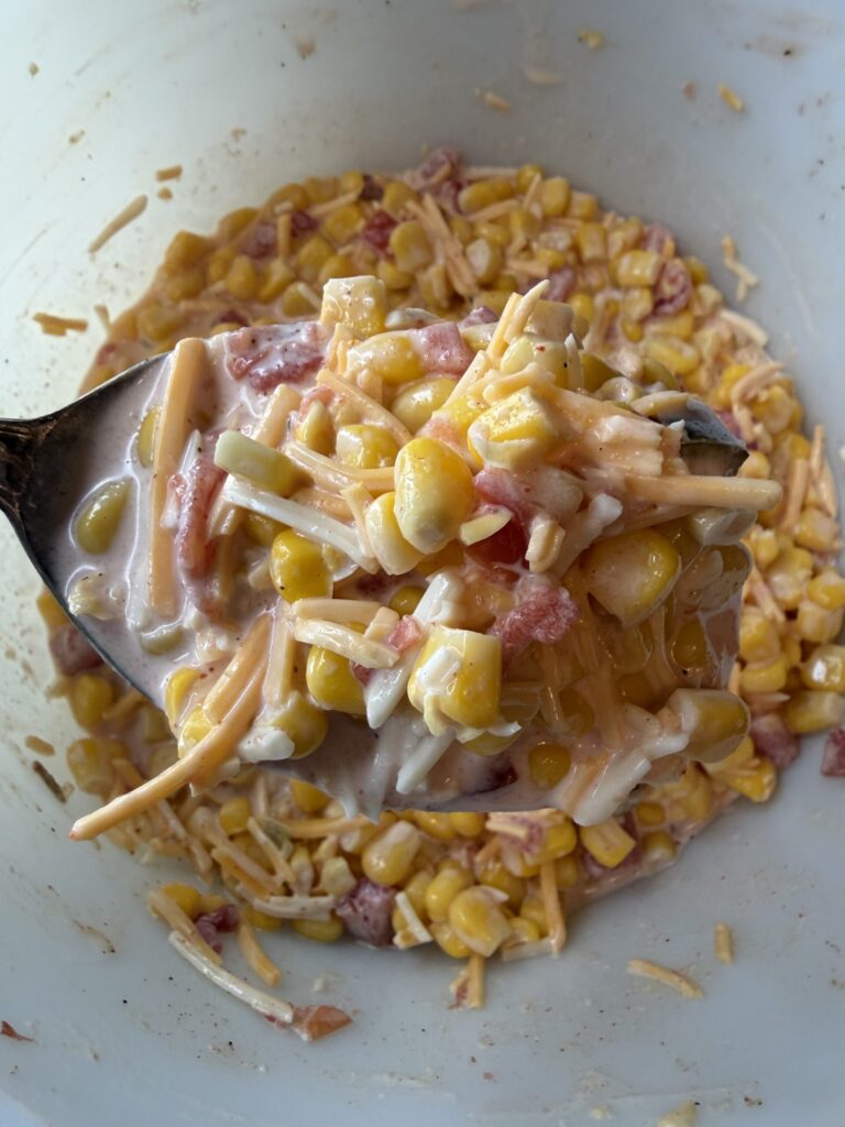 A closeup of a spoonful on homemade corn salsa, ready to use as a topping for pork carnitas. 