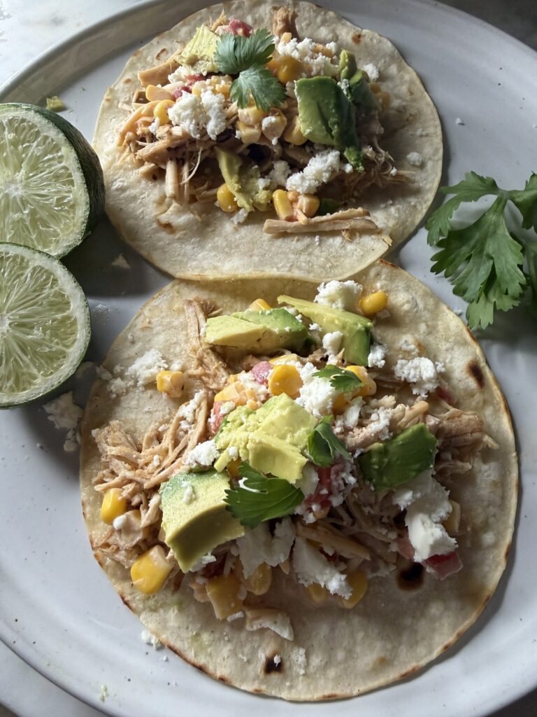 Homemade Pork Carnitas on a white plate served with lime wegdes.