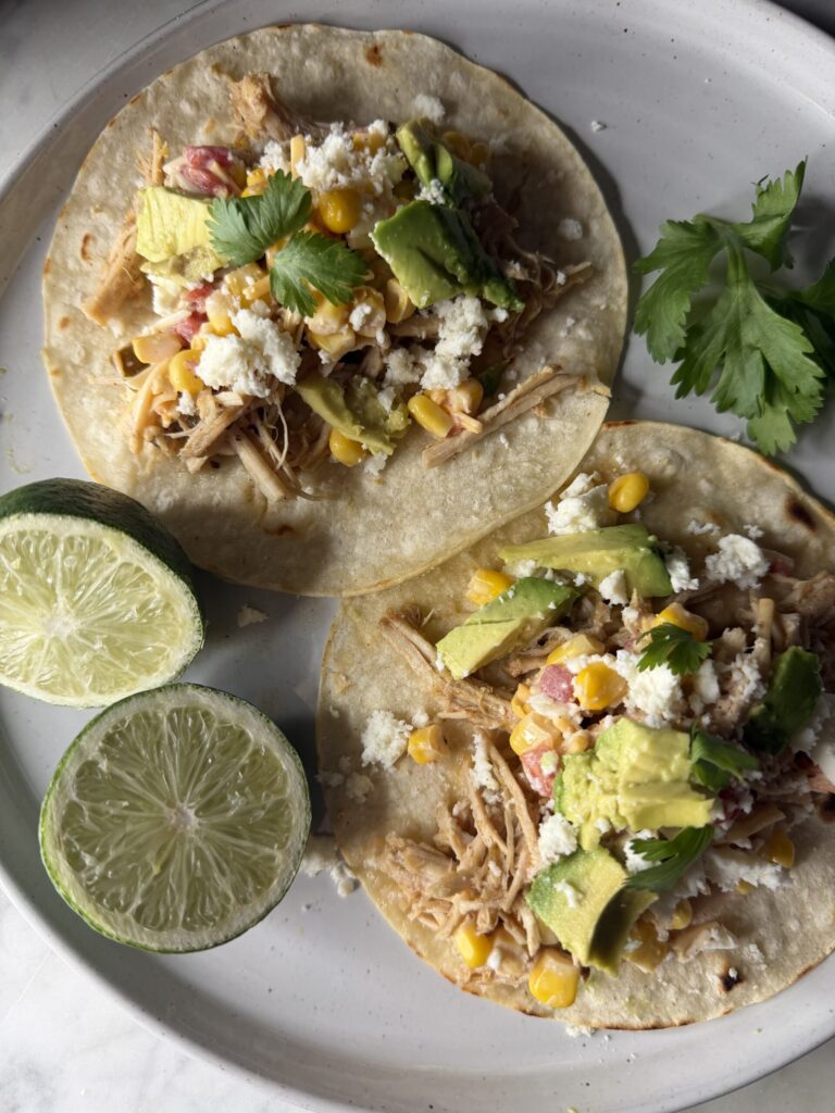 A delicious pork carnitas dinner on a plate with fresh lime wedges. 