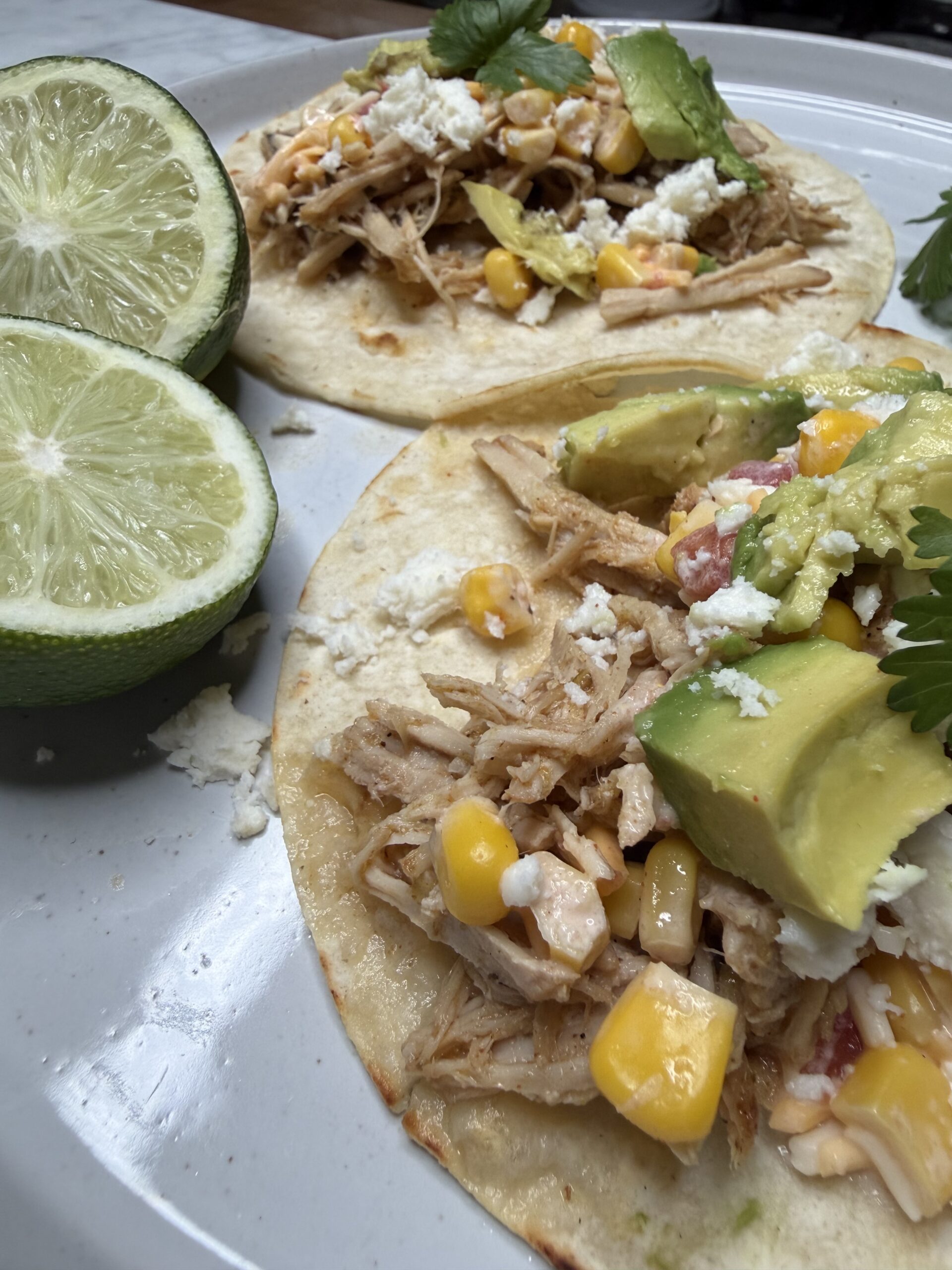 Juicy pork carnitas on a plate with corn salsa and fresh avocado.