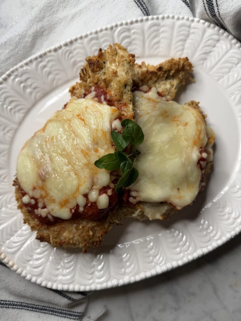 Two pieces of homemade chicken parmesan on a plate. 