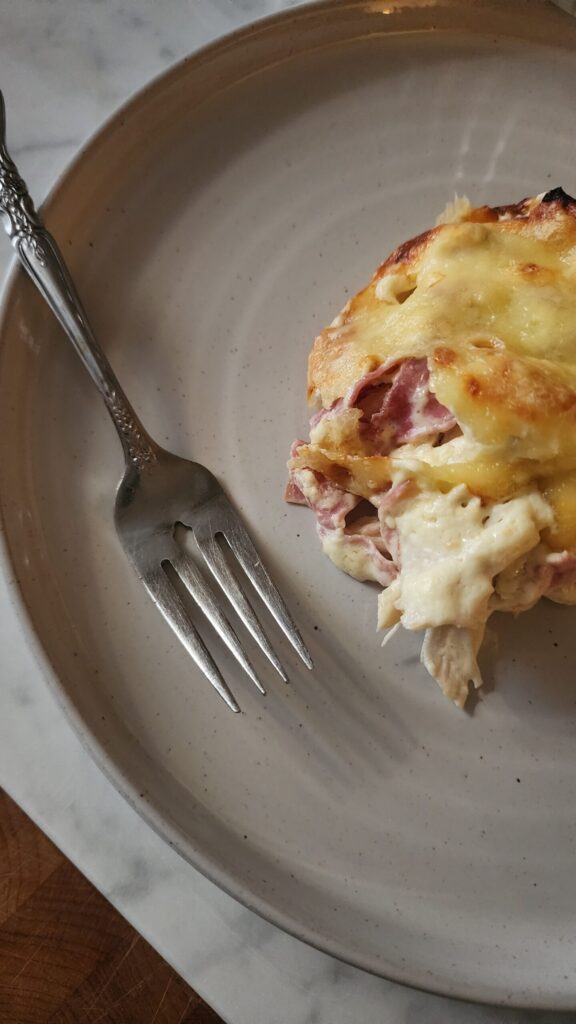 A serving of creamy low carb chicken cordon bleu casserole on a plate with a fork. 
