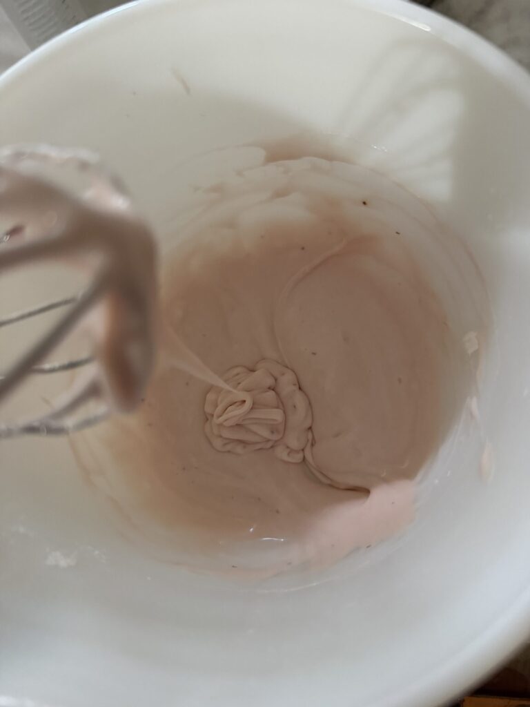 Powdered sugar, vanilla, cream, and strawberry simple syrup are mixed together to make strawberry glaze. 