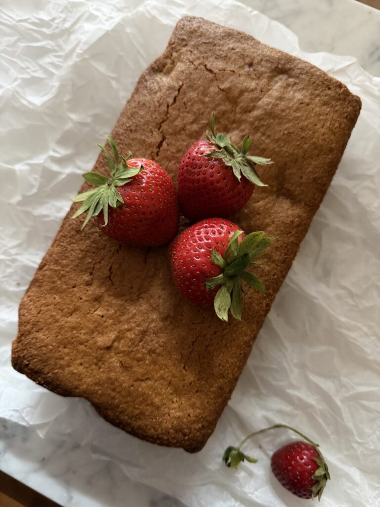A freshly baked loaf of unglazed sourdough strawberry quick bread on parchment paper. 