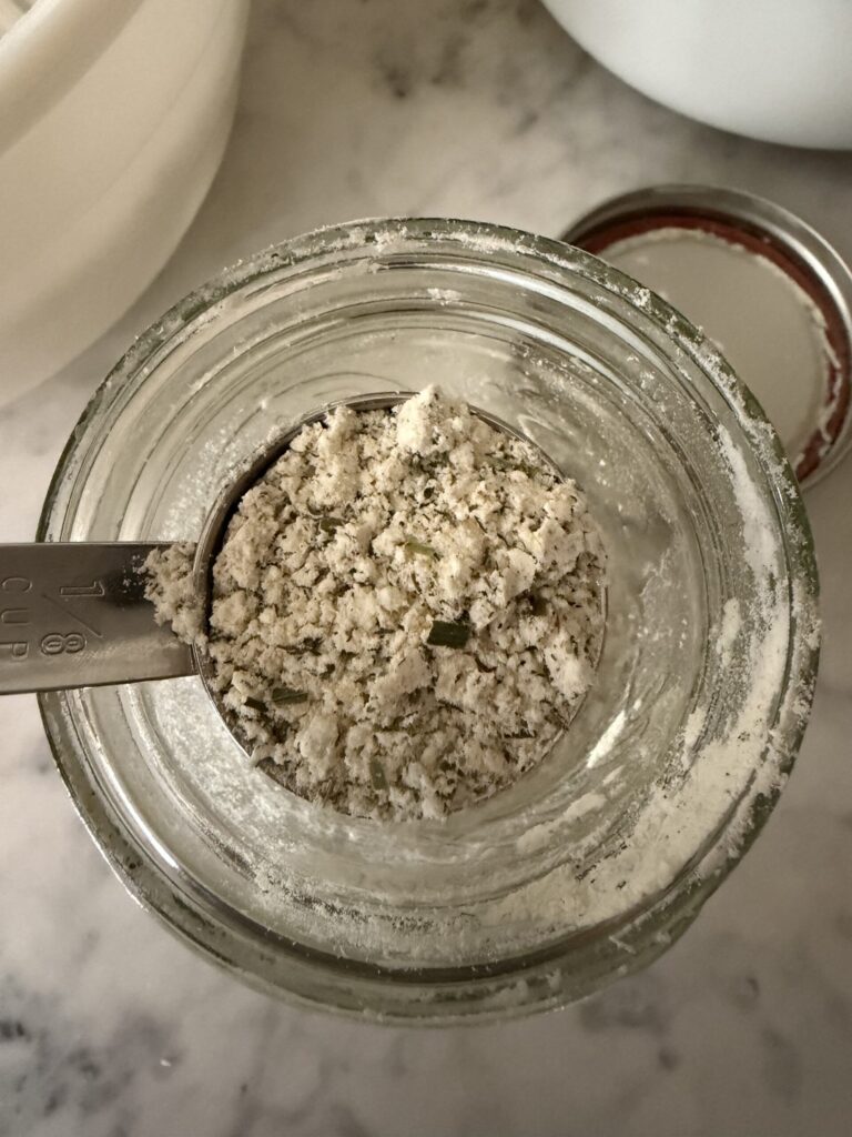 Homemade ranch seasoning mix in a jar being scooped with a silver tablespoon.