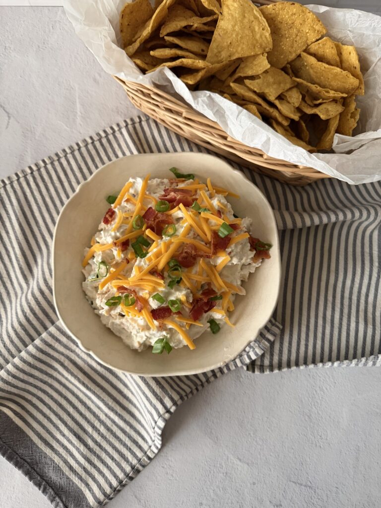 A big bowl of creamy chicken bacon ranch dip served with chips.