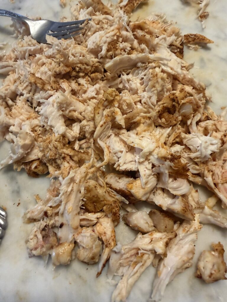 Shredded chicken is prepared on a marble surface for the breakfast burrito filling.