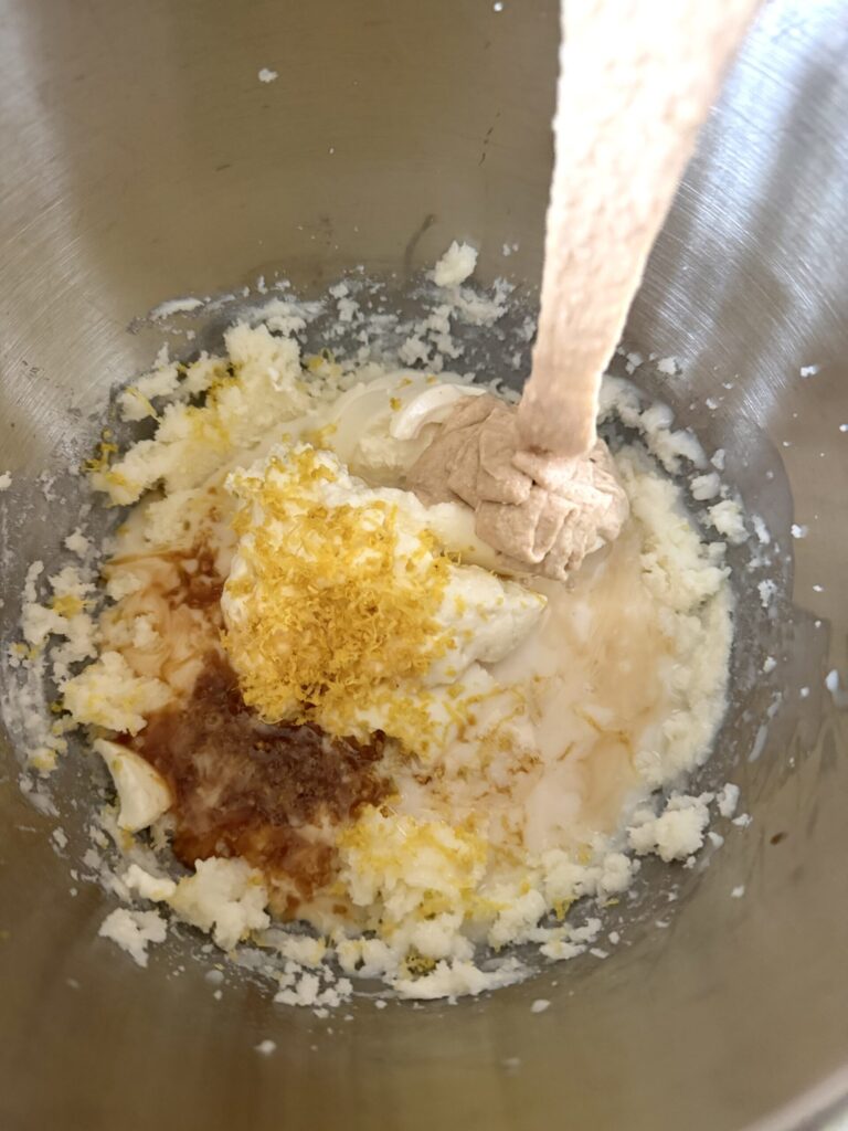 Lemon zest, sourdough starter, milk, butter, sugar, egg, and vanilla are added to a mixing bowl.