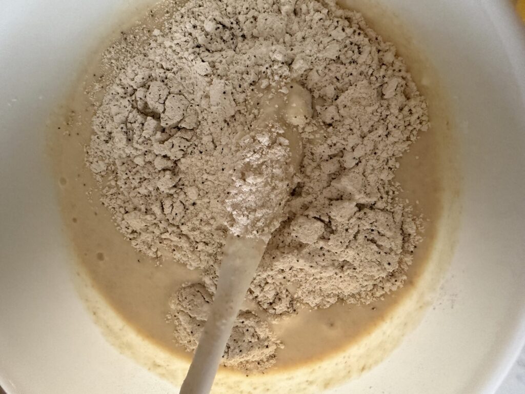 Dry ingredients are incorporated with wet ingredients to make Sourdough Lemon Poppy Seed Muffins.