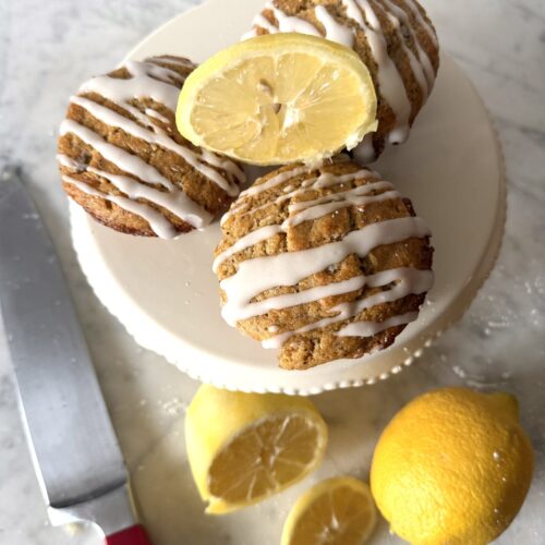 Delicious sourdough discard lemon poppy seed muffins with sliced lemons on a mini cake stand.