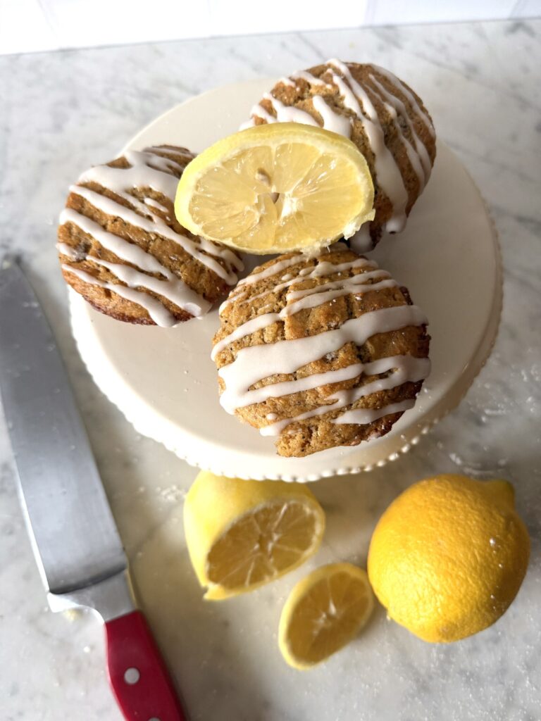 Delicious sourdough discard lemon poppy seed muffins with sliced lemons on a mini cake stand.
