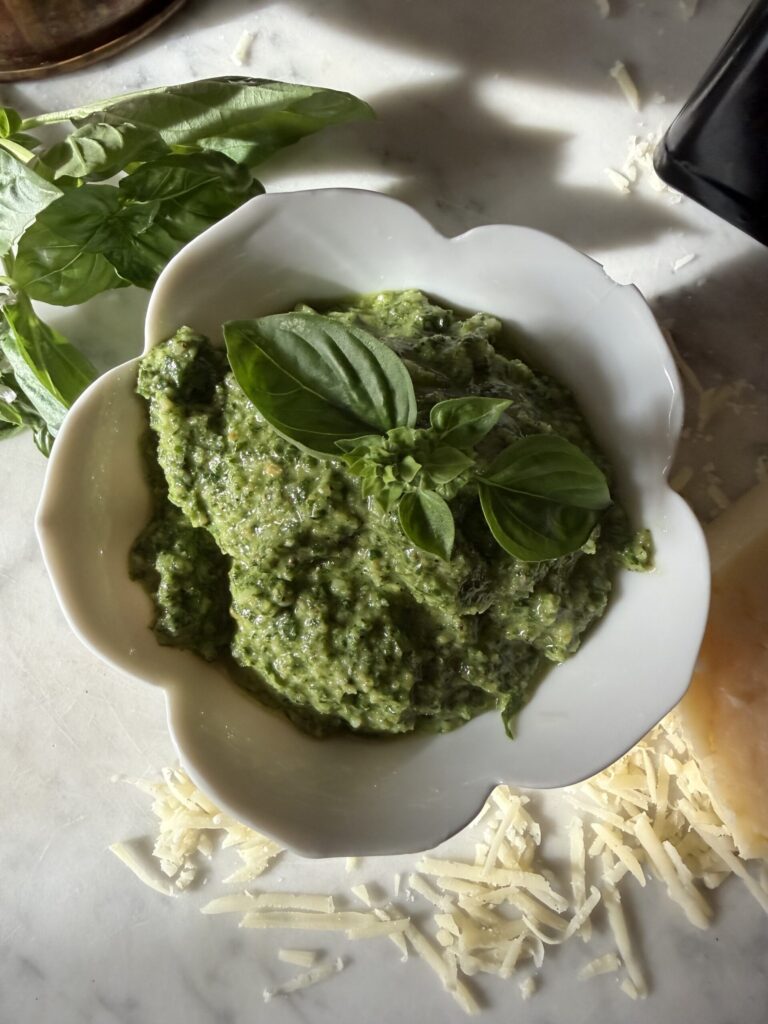 Homemade basil walnut pesto in a white bowl garnished with fresh basil leaves. 