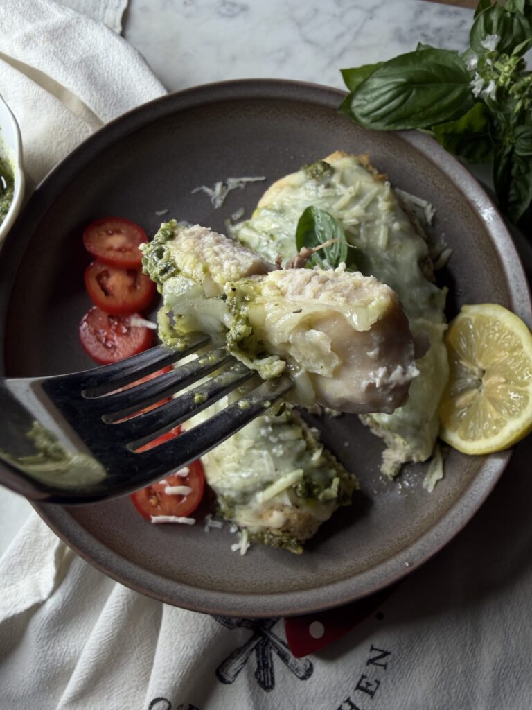 A bite of pesto caprese chicken with lemon and sliced garden tomatoes.