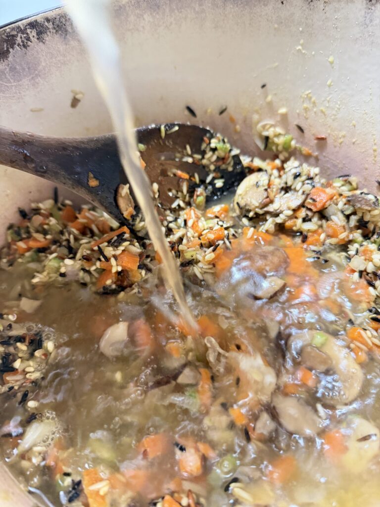 Chicken stock or bone broth is added to a vegetable and rice mixture to make soup.
