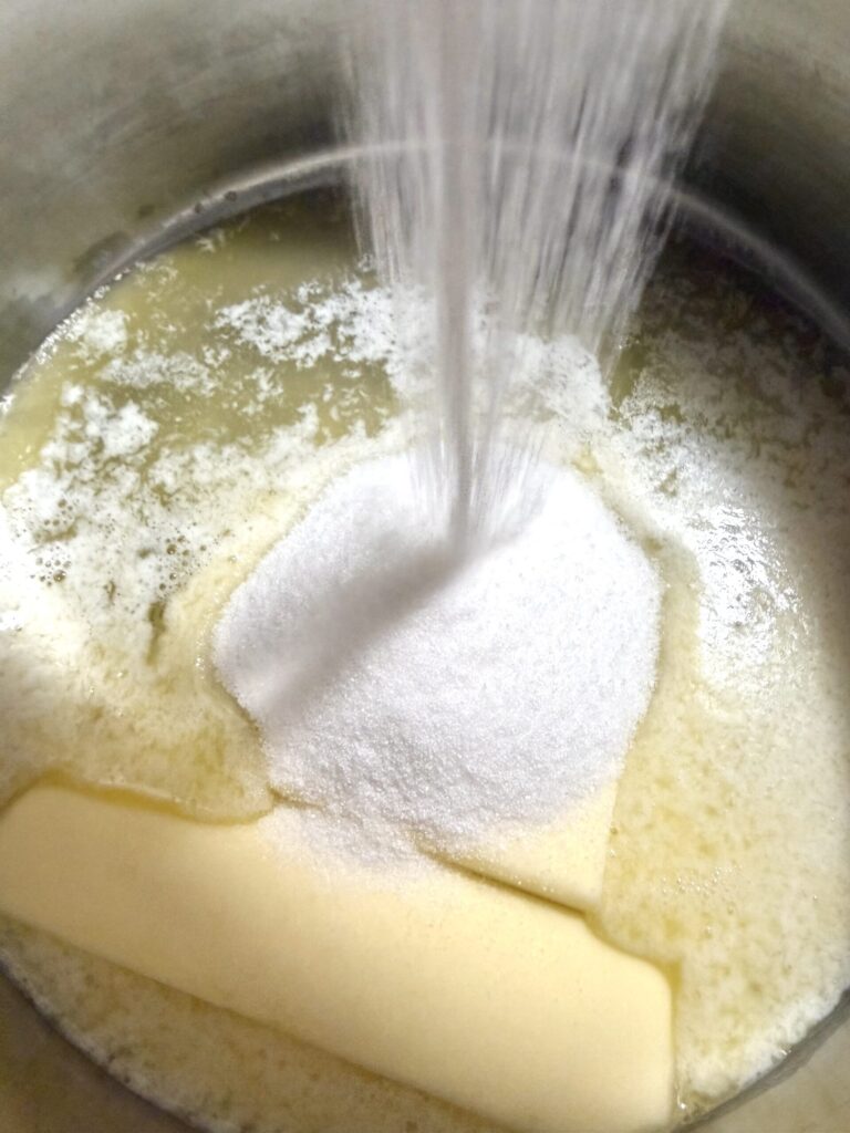 Sugar is added to a sauce pan of melted butter.