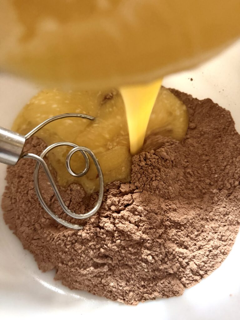 Wet ingredients are added to the dry ingredients to make pumpkin swirl brownies.