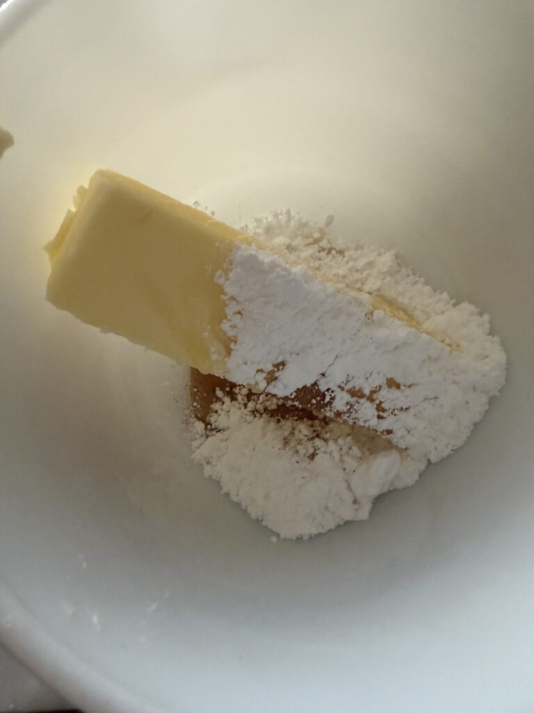 Butter, powdered sugar, honey, and cinnamon in a white mixing bowl