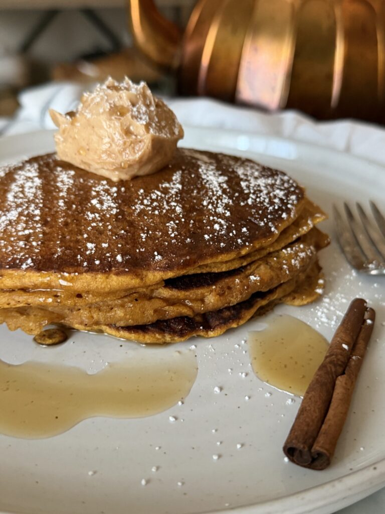 Pumpkin spice pancakes with drizzled warm maple syrup topped with a dollop of cinnamon sugar honey butter
