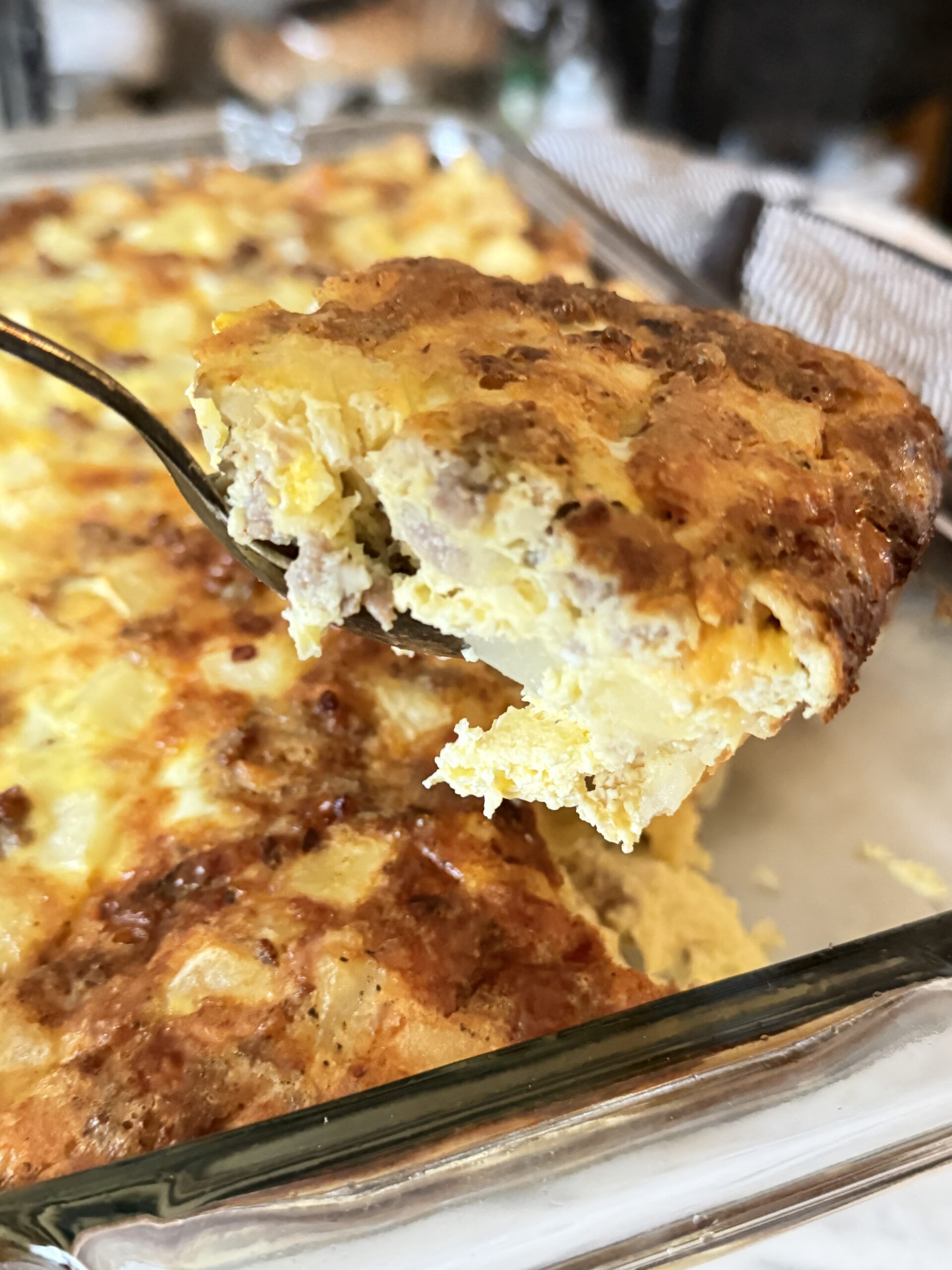 A large serving of cheesy potato, egg, and sausage casserole.
