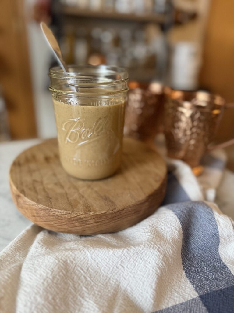 Homemade from scratch pumpkin sauce in a jar with a wooden trivet and tea towel