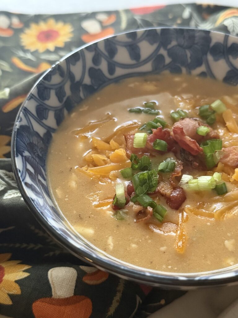 Beer cheese soup with toppings on a fall tea towel