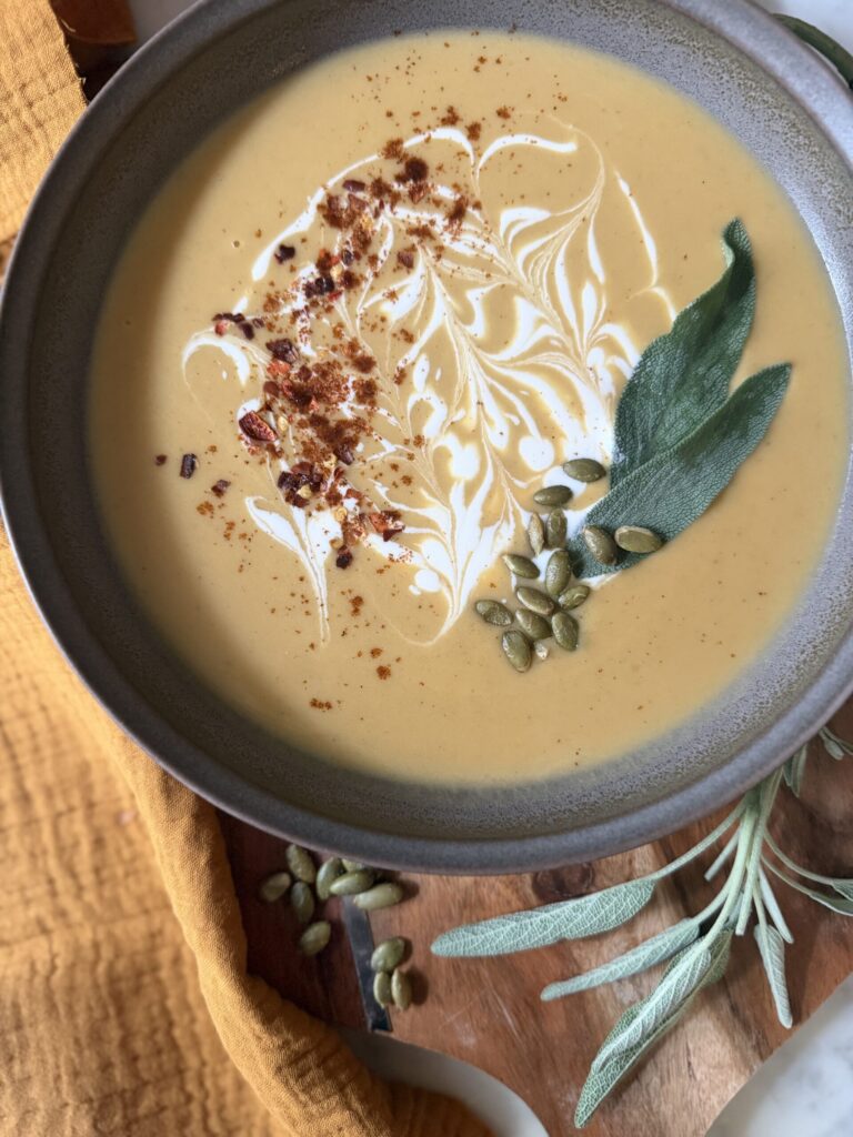 A creamy soup of sweet potatoes and butternut squash with a swirl of cream and hot pepper flakes