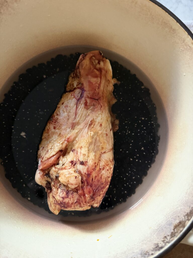 A large pot full of black beans with water and a smoked ham hock