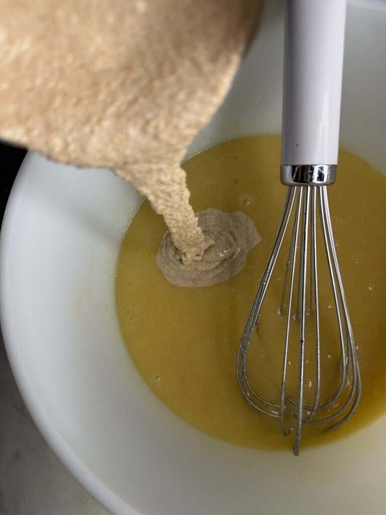 Sourdough discard is added to a bowl of wet ingredients for cornbread