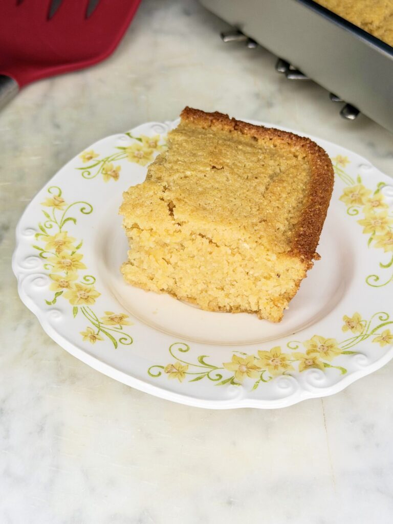 A slice of golden sourdough cornbread on a decorative plate