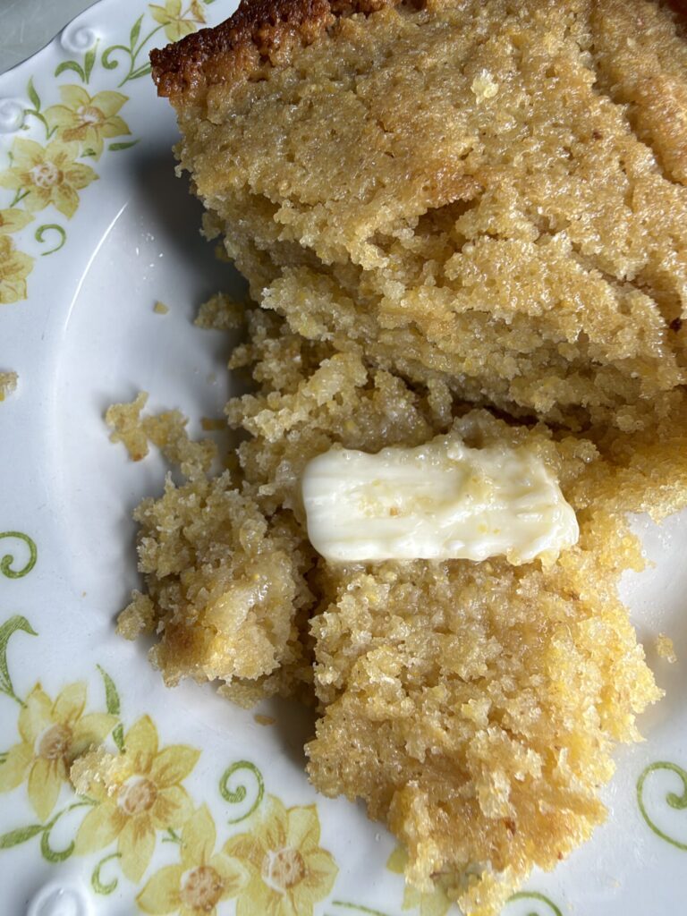 A pat of butter is melting into warm sourdough cornbread on a plate