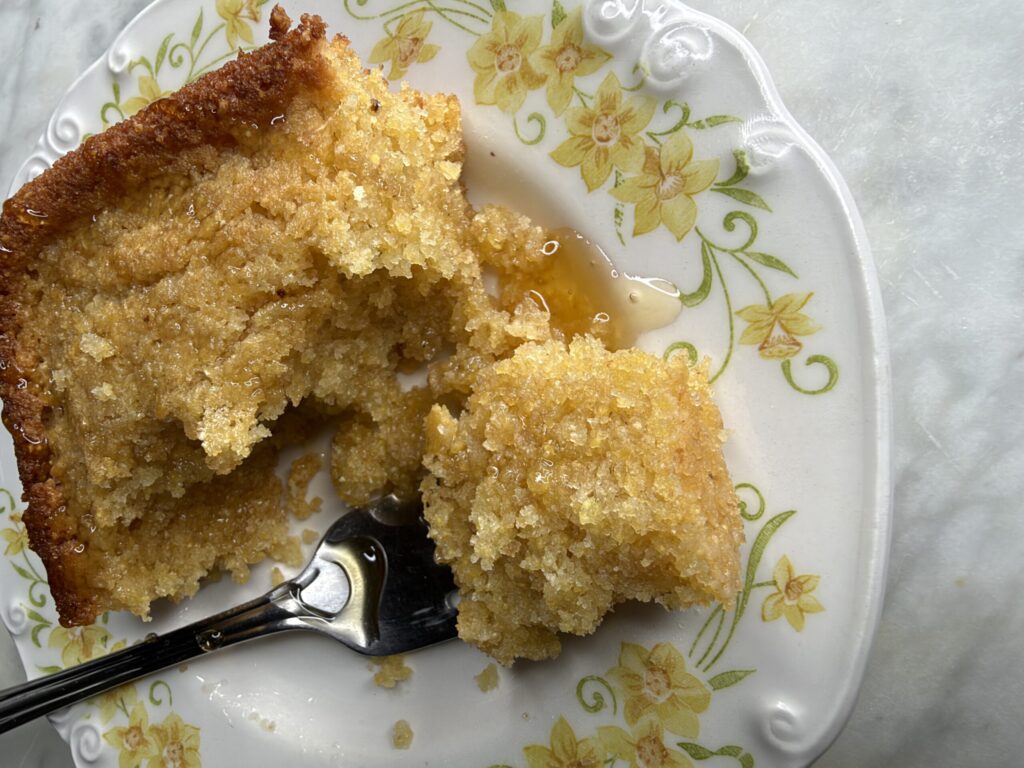 Warm sourdough cornbread slice on a plate drizzled with sweet honey
